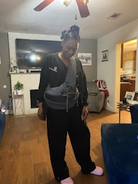 a woman standing in a living room with a sling bag