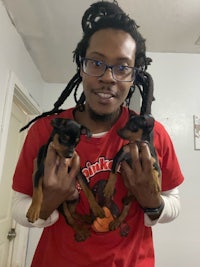 a man with dreadlocks holding two puppies