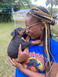 a woman with dreadlocks holding a small puppy