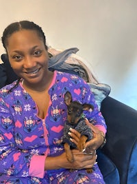 a woman in pajamas holding a small dog