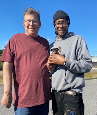 two men standing next to each other holding a trophy