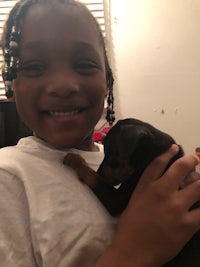 a young girl holding a small black and brown dog